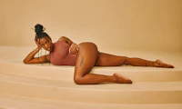 Image of a Black female presenting person laying provocatively on stairs.